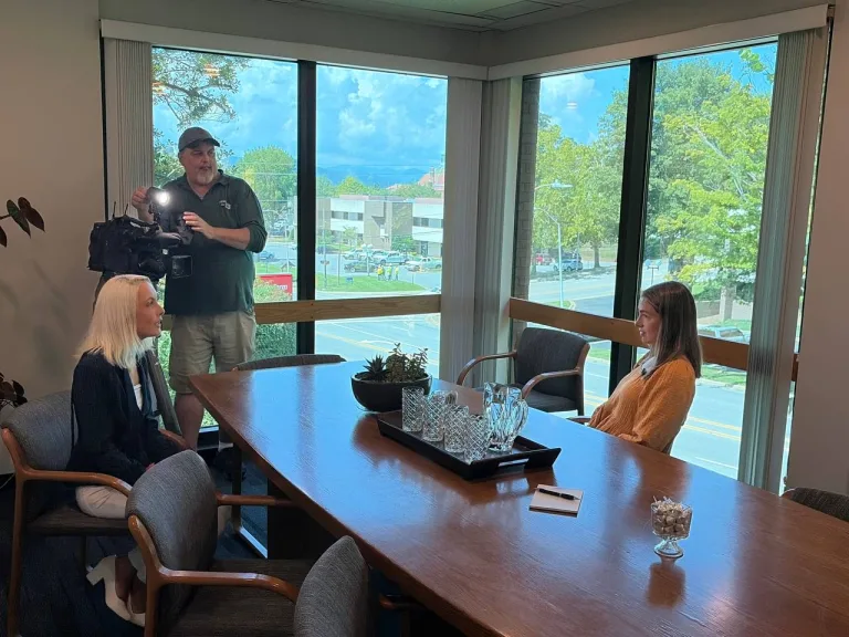 Ruth Hays speaks with a WLOS camera crew inside the ACT Advisors office in Asheville.